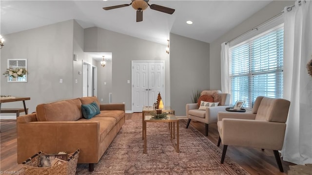 living room with hardwood / wood-style floors, ceiling fan with notable chandelier, and vaulted ceiling