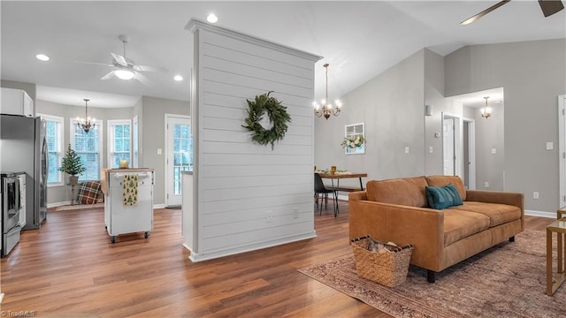 living room featuring hardwood / wood-style floors, ceiling fan with notable chandelier, and vaulted ceiling