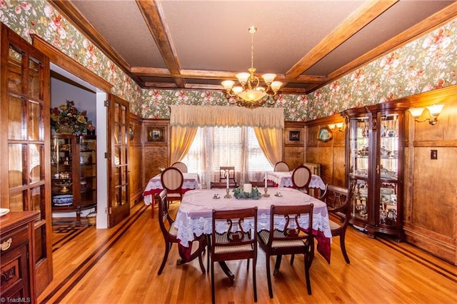 dining space with beam ceiling, a chandelier, and light wood-type flooring