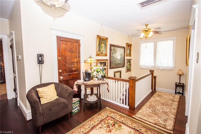 sitting room featuring ceiling fan, crown molding, and dark hardwood / wood-style flooring