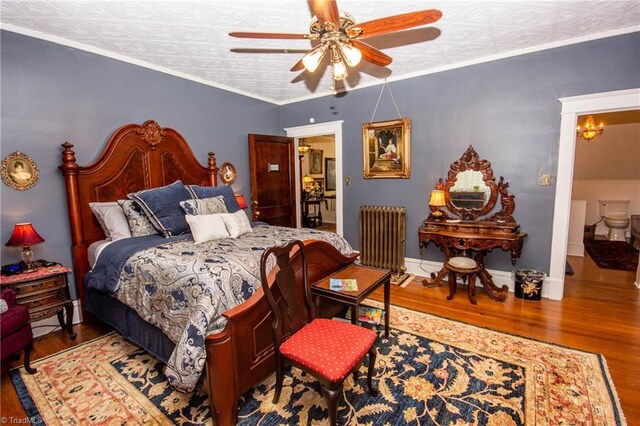 bedroom with radiator heating unit, ceiling fan with notable chandelier, ornamental molding, and hardwood / wood-style flooring