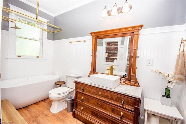 bathroom with crown molding, toilet, vanity, hardwood / wood-style floors, and a washtub