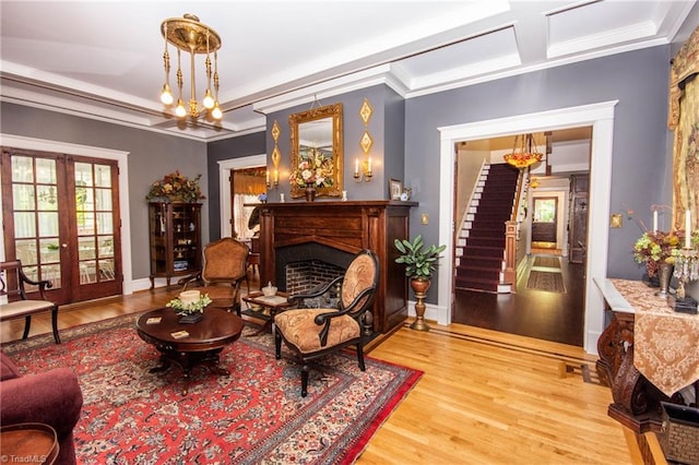 living area with an inviting chandelier, ornamental molding, light hardwood / wood-style floors, and french doors