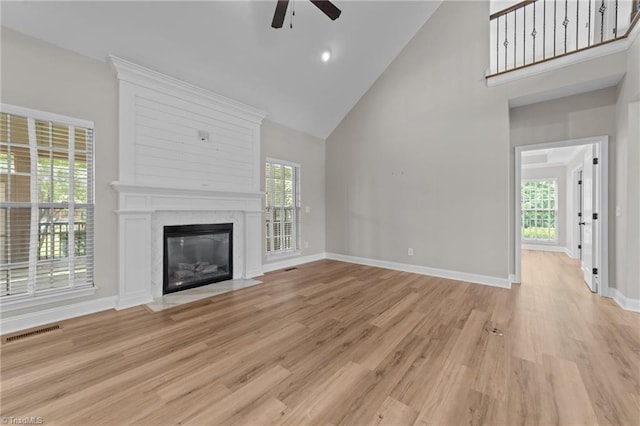unfurnished living room featuring high vaulted ceiling, ceiling fan, light wood-type flooring, and healthy amount of natural light