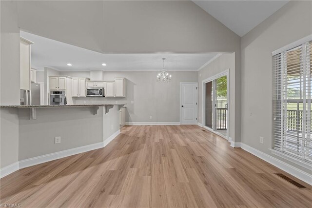 unfurnished living room with a chandelier, light wood finished floors, vaulted ceiling, baseboards, and recessed lighting