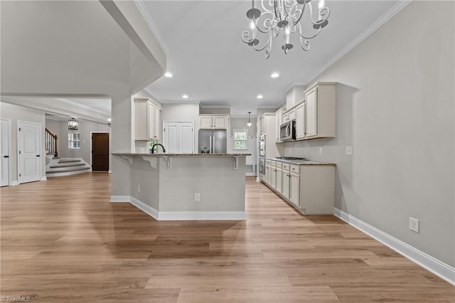 kitchen featuring stainless steel appliances, crown molding, a kitchen bar, a peninsula, and a chandelier