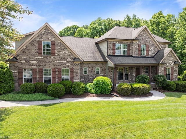 view of front of property with a front lawn, brick siding, and a shingled roof