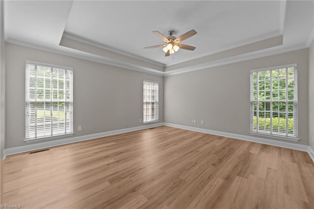 unfurnished room featuring a tray ceiling, crown molding, ceiling fan, light wood-type flooring, and baseboards