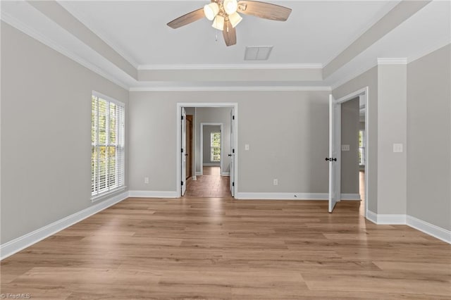 spare room with a ceiling fan, crown molding, light wood-style floors, and baseboards