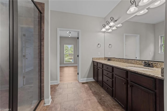 bathroom with plenty of natural light, a stall shower, double vanity, and baseboards
