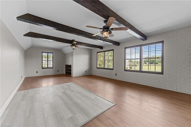 unfurnished living room with a ceiling fan, brick wall, wood finished floors, a fireplace, and baseboards