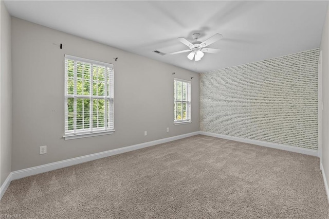 carpeted spare room featuring baseboards, ceiling fan, plenty of natural light, and wallpapered walls