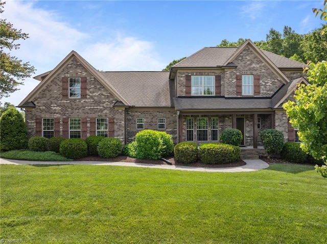 view of front facade featuring brick siding, a front lawn, and a shingled roof