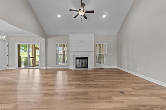 unfurnished living room with high vaulted ceiling, a large fireplace, a ceiling fan, baseboards, and light wood-style floors