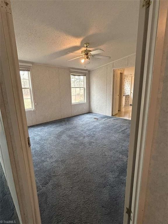 carpeted empty room with a ceiling fan and a textured ceiling