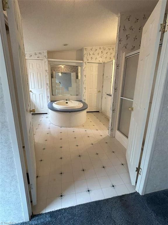 full bathroom with a textured ceiling, a stall shower, and wallpapered walls