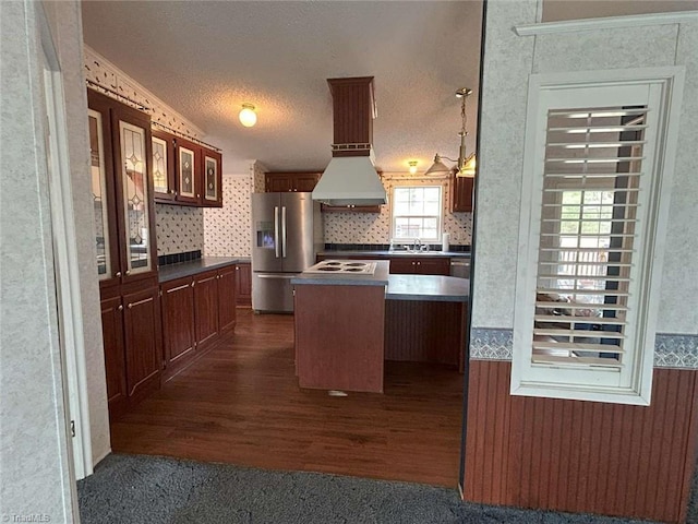 kitchen with a sink, wallpapered walls, stainless steel fridge, a textured ceiling, and dark wood-style flooring