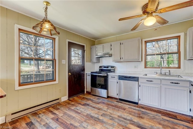 kitchen with wood finished floors, a sink, stainless steel appliances, under cabinet range hood, and baseboard heating