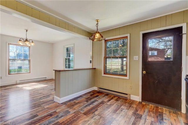 foyer entrance with a baseboard heating unit, a healthy amount of sunlight, and hardwood / wood-style floors