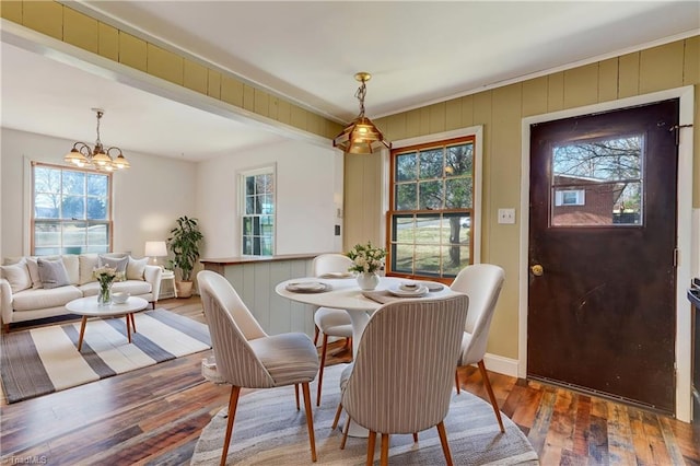 dining space with a chandelier, a healthy amount of sunlight, baseboards, and wood finished floors