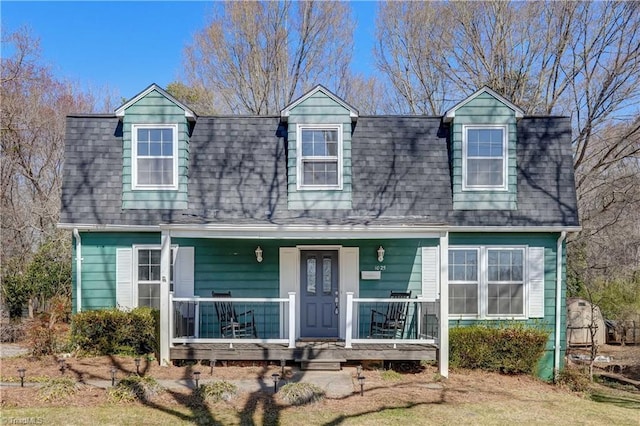 dutch colonial featuring covered porch and a shingled roof