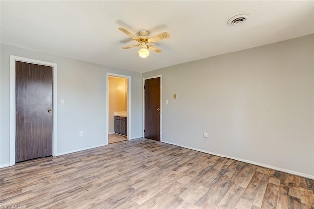 empty room featuring baseboards, visible vents, a ceiling fan, and light wood-style floors