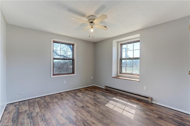 spare room with baseboard heating, plenty of natural light, a textured ceiling, and wood finished floors