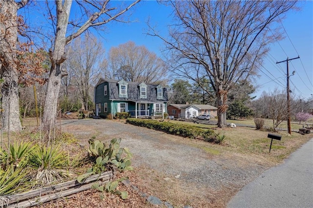 colonial inspired home featuring a gambrel roof, a front yard, and driveway