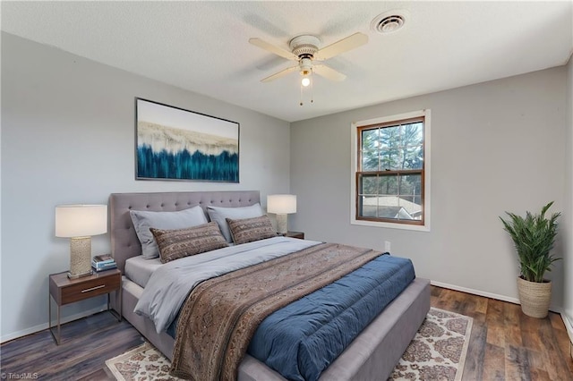 bedroom with visible vents, a textured ceiling, baseboards, and wood finished floors