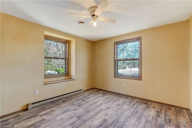 unfurnished room featuring baseboard heating, wood finished floors, and wallpapered walls