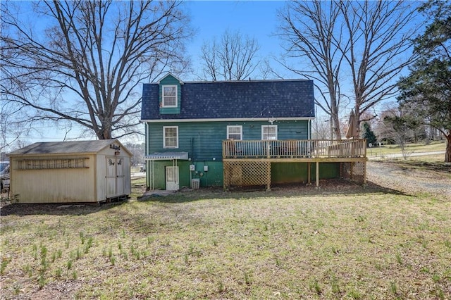 back of house featuring an outbuilding, a lawn, a storage shed, roof with shingles, and a wooden deck