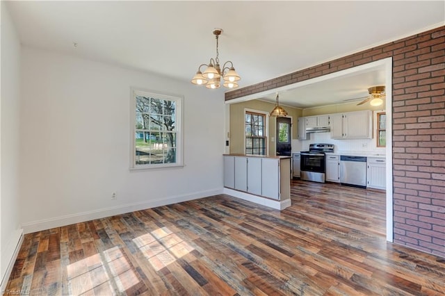 kitchen with pendant lighting, under cabinet range hood, dark wood finished floors, appliances with stainless steel finishes, and a peninsula