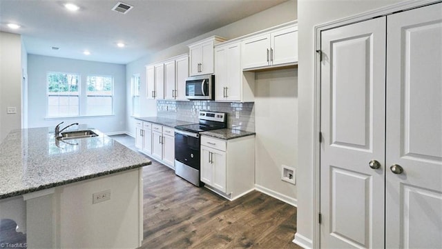 kitchen with sink, light stone counters, a center island with sink, stainless steel appliances, and white cabinets