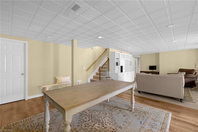 dining room with light wood finished floors, visible vents, stairs, and baseboards