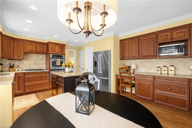 kitchen featuring light stone counters, pendant lighting, light wood finished floors, stainless steel appliances, and an inviting chandelier