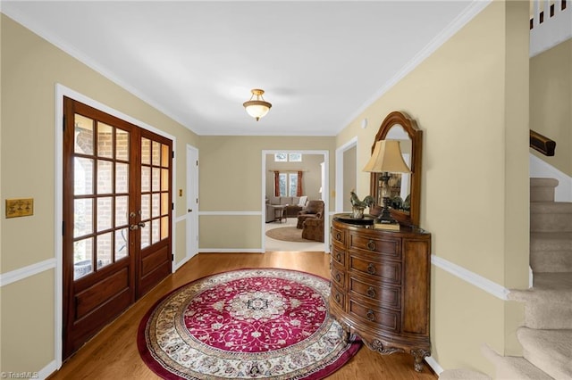 entryway featuring crown molding, stairway, wood finished floors, and french doors