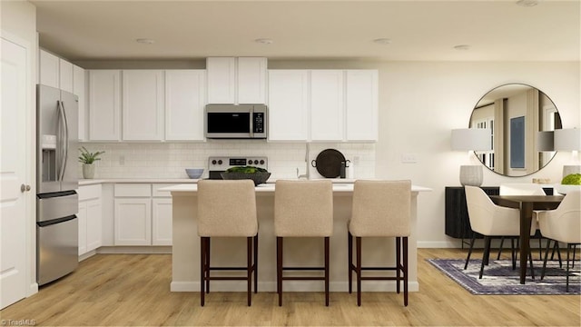 kitchen featuring stainless steel appliances, light countertops, white cabinetry, and a kitchen bar