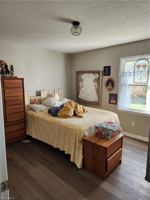 bedroom with a textured ceiling and dark hardwood / wood-style floors