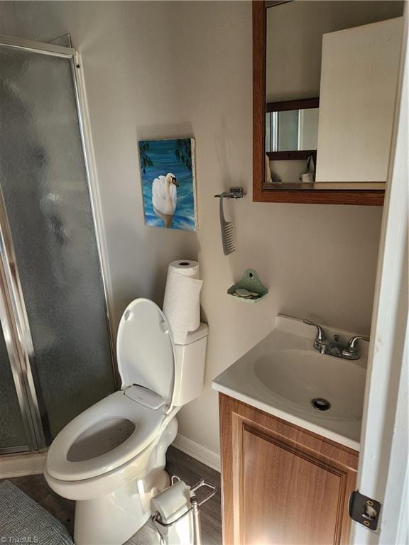 bathroom featuring vanity, hardwood / wood-style flooring, toilet, and a shower with shower door