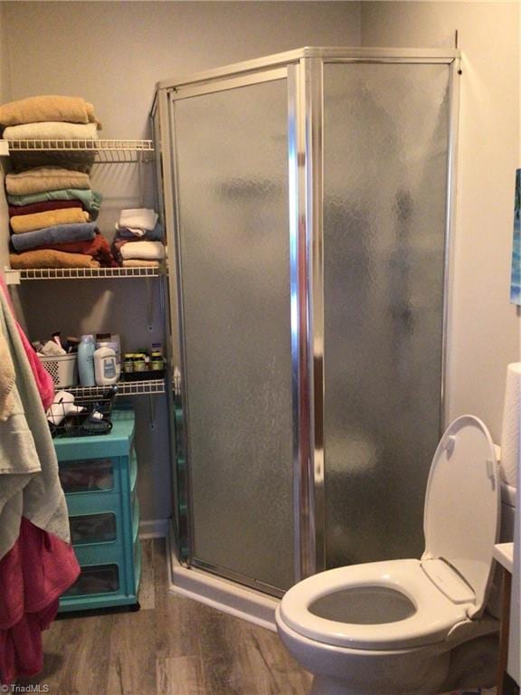 bathroom with a shower with door, wood-type flooring, and toilet