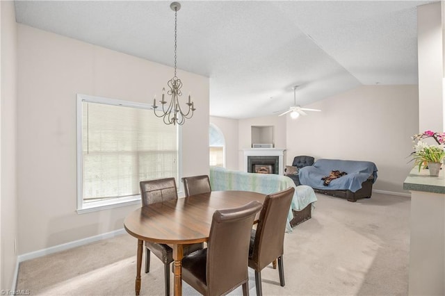 dining area with a notable chandelier, a wealth of natural light, light colored carpet, and vaulted ceiling