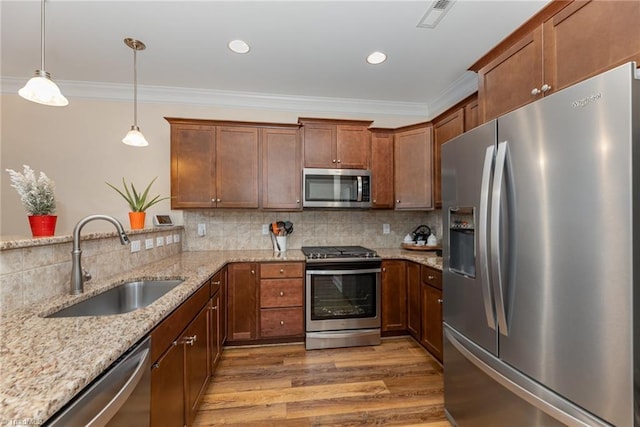 kitchen featuring crown molding, appliances with stainless steel finishes, a sink, and decorative backsplash