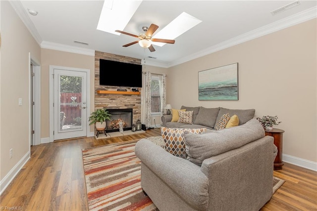 living room featuring a fireplace, a skylight, wood finished floors, and visible vents