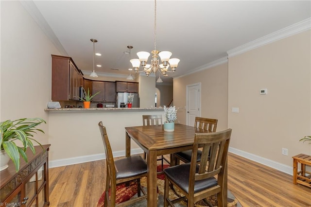 dining space featuring ornamental molding, light wood finished floors, an inviting chandelier, and baseboards