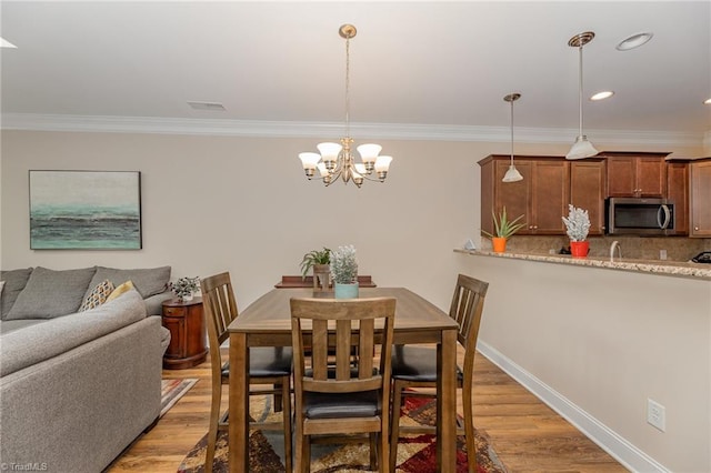 dining room featuring ornamental molding, light wood-style flooring, and baseboards