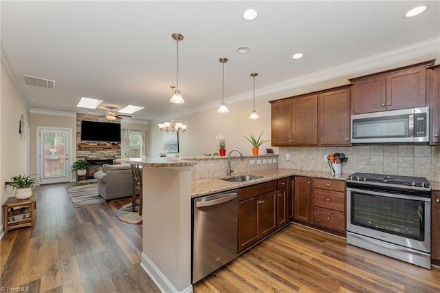 kitchen featuring stainless steel appliances, a skylight, a sink, visible vents, and open floor plan