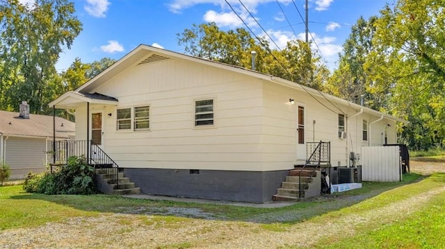 rear view of house with central AC unit and a yard