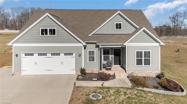 craftsman-style home featuring concrete driveway, a front lawn, a shingled roof, an attached garage, and a porch