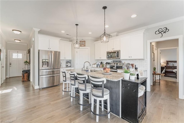 kitchen with light stone counters, appliances with stainless steel finishes, a kitchen breakfast bar, white cabinetry, and a sink