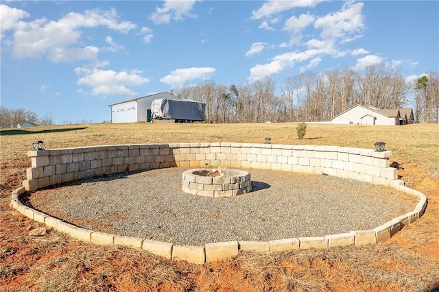view of yard with a fire pit, a detached garage, and an outdoor structure